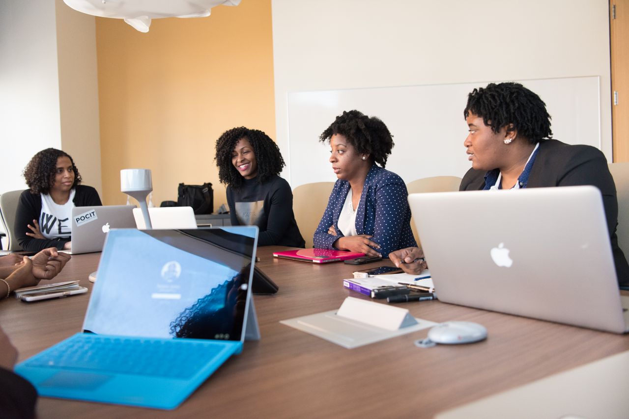 The Art of Drawing Readers In: Your attractive post title goes here Black women collaborating with laptops in an office meeting, enhancing teamwork and technology.