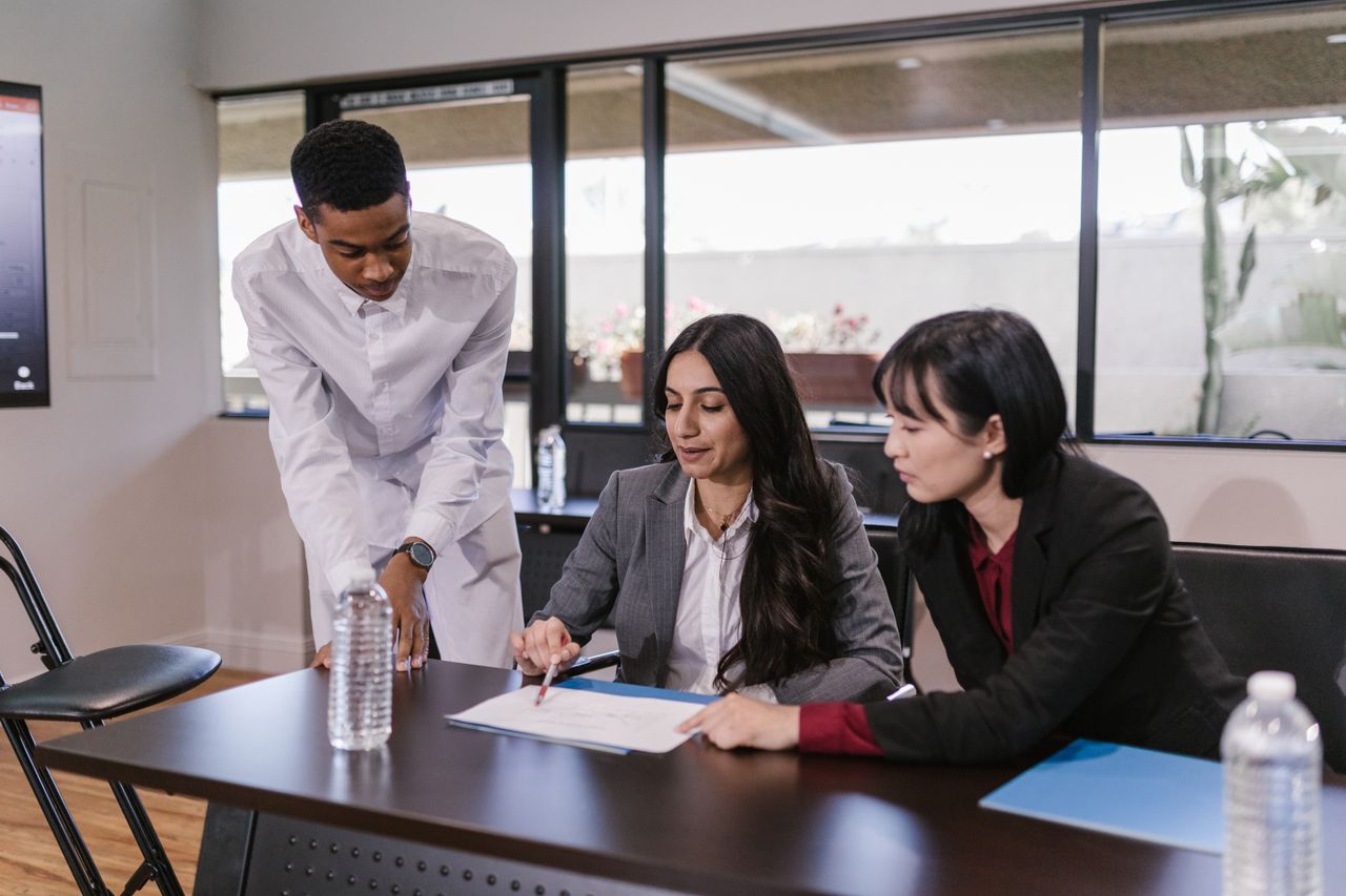 Three professionals discussing a project in a modern conference room setting.